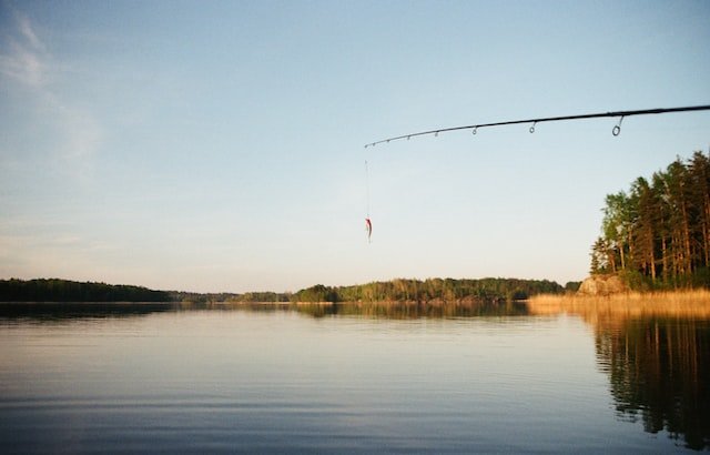 a fishing rod and lure hanging over a large lake